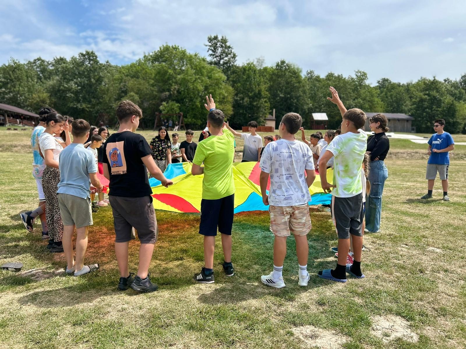 Children and volunteers playing a parachute game outdoors in Romania